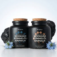⁠ Nigela Schwarzkümmelöl Kapseln Bundle – Daily und Akut im Set, zwei schwarze Gläser mit Korken, blaue Schwarzkümmelblüten ⁠